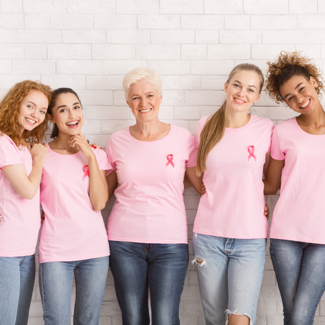A diverse group of women wearing pink shirts and breast cancer awareness ribbons.